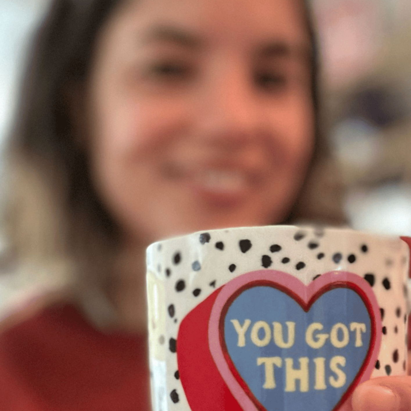 Person holding a mug with 'You Got This' text, blurred background